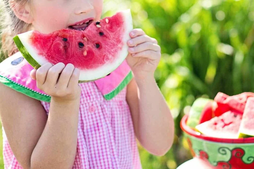 A young girl eating a slice of watermelon