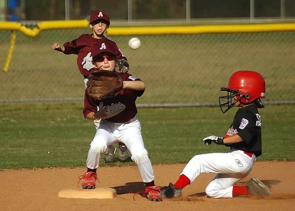 A young boy playing baseball is about to catch the ball with his glove