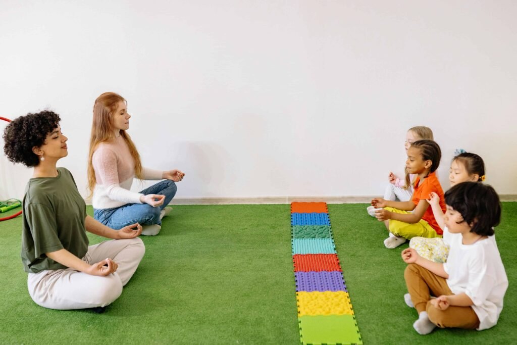 2 Teachers and 4 Children Sitting on the Floor and Meditating